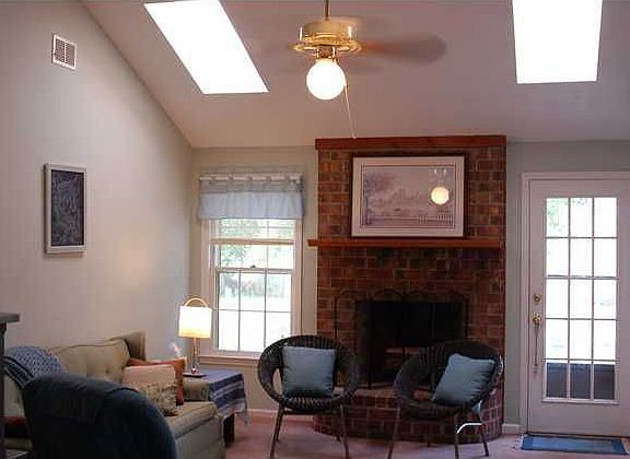 great room with vaulted ceiling, woodburning fireplace, and skylights