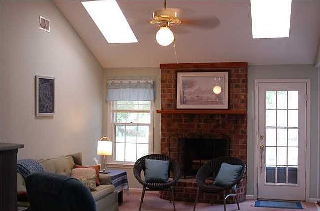 great room with vaulted ceiling, woodburning fireplace, and skylights