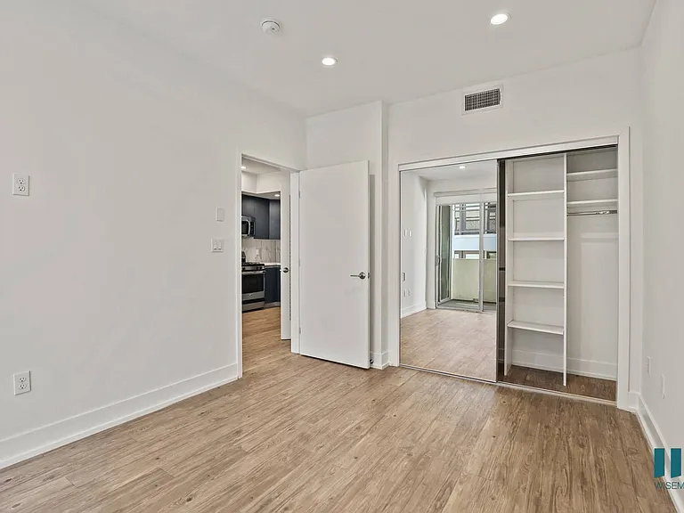 Bedroom with Closet with Built-In Shelving, Vinyl Flooring, and Recessed Lighting