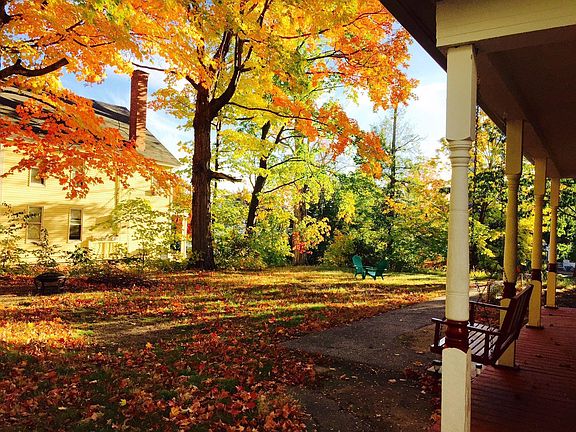 View of this apartment's covered porch with porch swing overlooking the yard and 100 year old maple trees.
