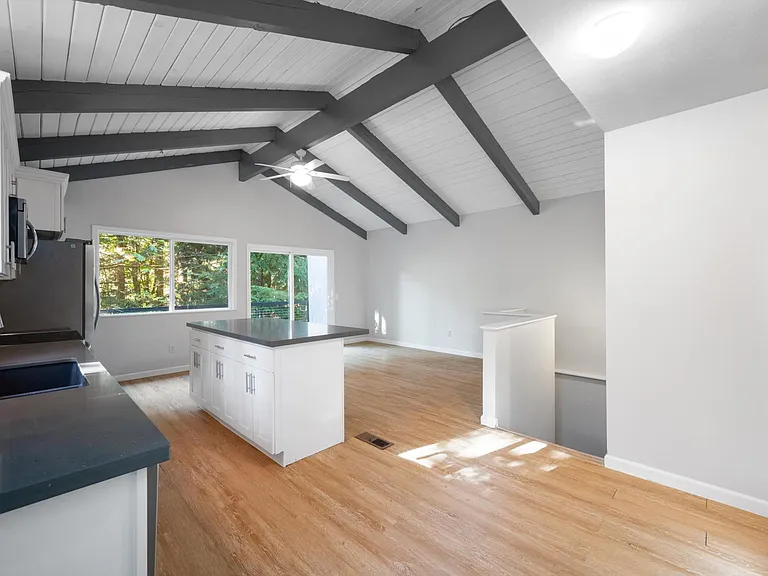 Updated bright & open concept kitchen with quartz counter tops, stainless appliances & vaulted ceilings. Sliding glass doors to private back patio.