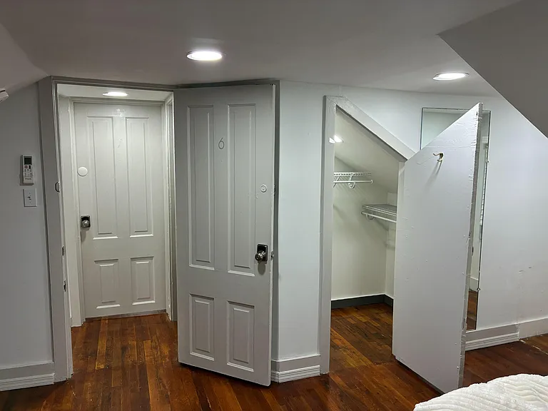 Upper-level hallway/landing with hardwood floors, recessed lighting, and a built-in storage closet with shelving.