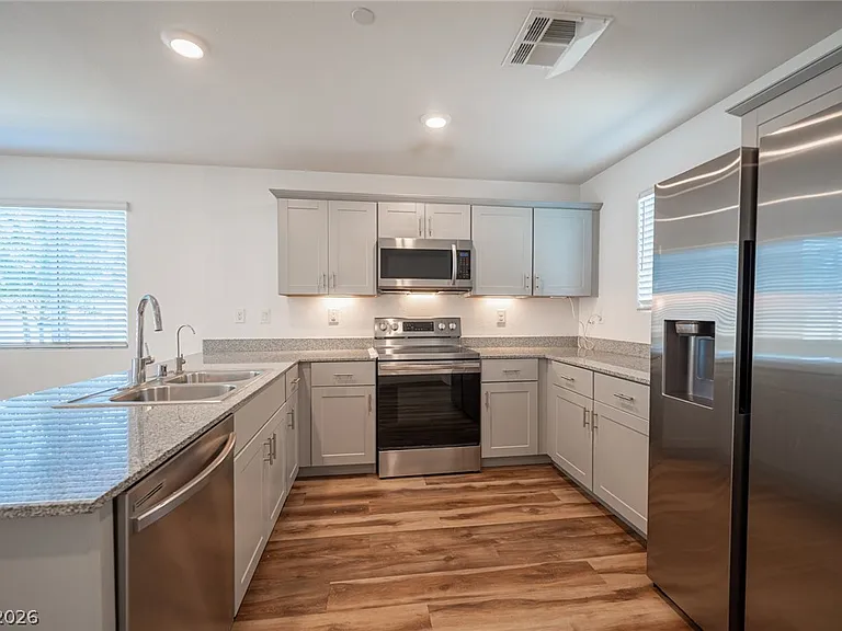 The kitchen includes a stainless-steel refrigerator/freezer, electric range/oven, microwave, dishwasher, disposal, and filtered water.