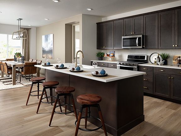 A modern and spacious kitchen with dark wood cabinets, a large island with bar stools, and various a