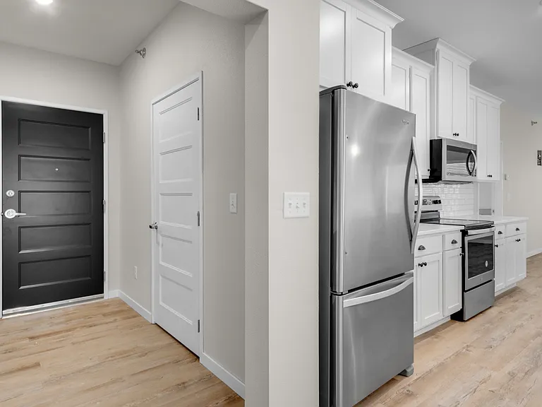 Modern kitchen entrance featuring sleek stainless steel appliances, elegant cabinetry, and inviting wood flooring. Modern kitchen entrance featuring sleek stainless steel appliances, elegant cabinetry, and inviting wood flooring.