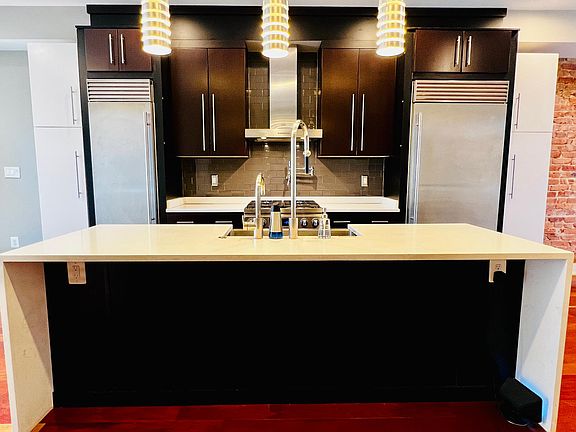 Gourmet kitchen with quartz countertops, two luxury refrigerators, microwave drawer, deep stainless steel sink, dishwasher, high end gas stove, and pot filler. Added pantries on both sides of the refrigerators with pull out drawers. Installed pull out dra