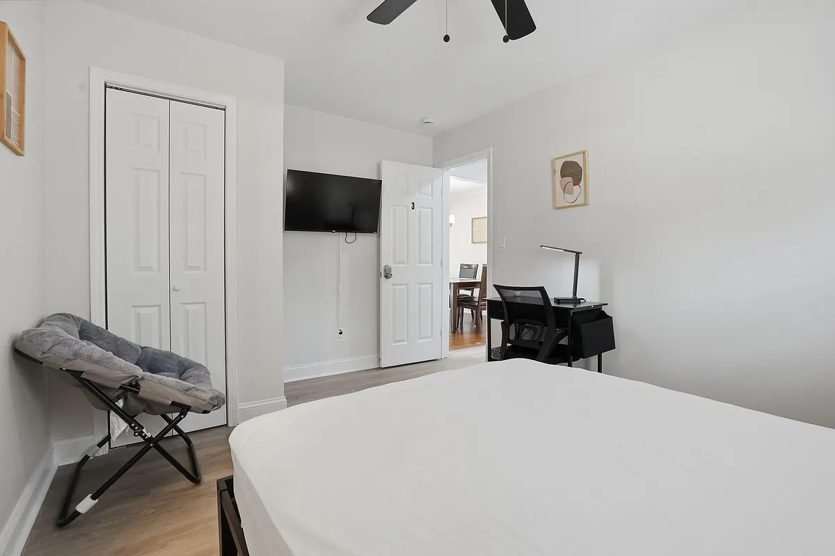 Private bedroom with a wall-mounted TV, dedicated desk workspace, and a closet with sliding doors for easy storage. - Dodson Dr SW