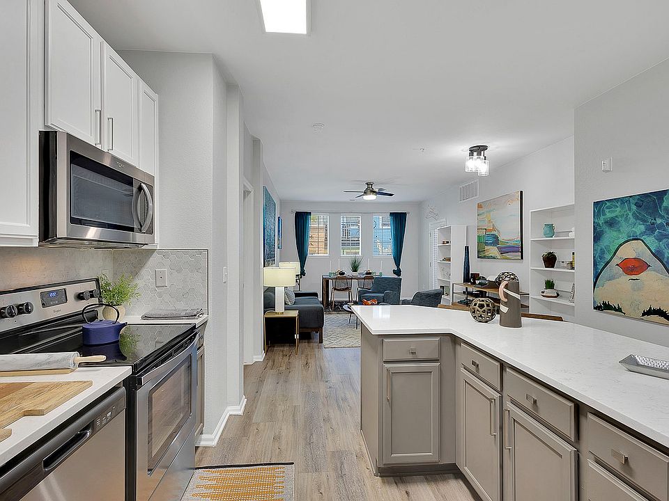 Modern open-plan kitchen and living area with sleek cabinetry, stainless steel appliances, and vibrant decor, offering a stylish and inviting ambiance.