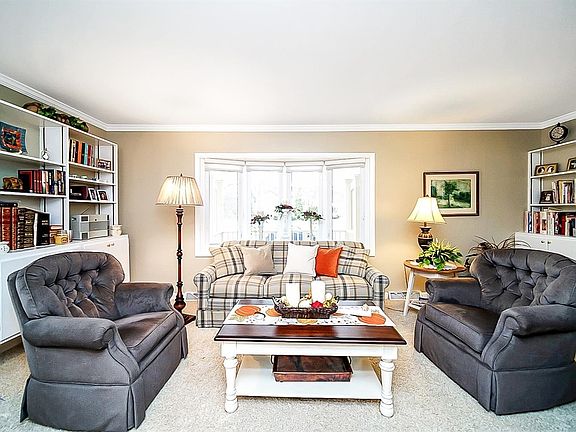 The bright and cheery living room has been upgraded with crown molding, bow window & custom built-ins.