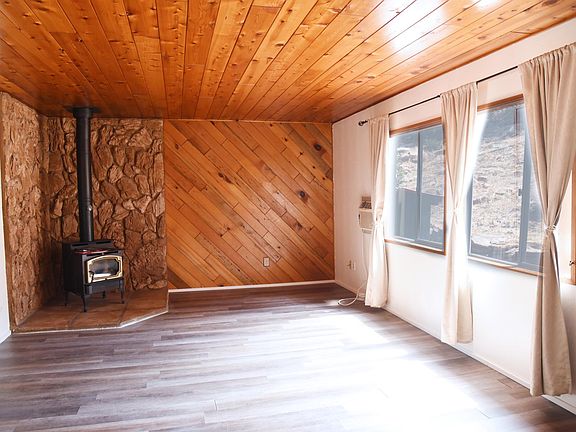 Living room with propane gas stove to keep you cozy in the winter. In-wall air conditioning unit next to the window.