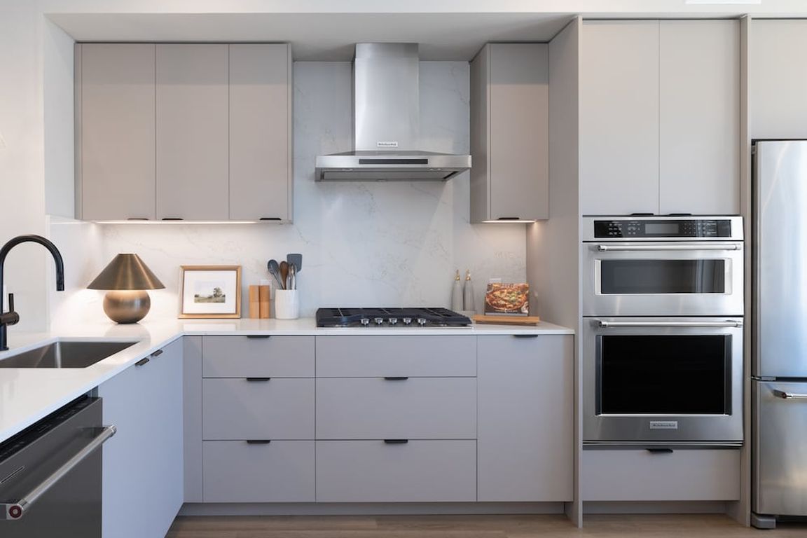 Signature Collection I 3-Bedroom Townhome Kitchen with light grey cabinetry, white marbled quartz countertops, and upgraded stainless steel appliances