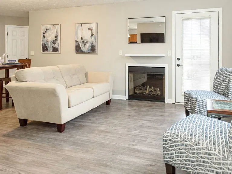 View of great room from foyer showing living area with fireplace and door to private patio and dining area