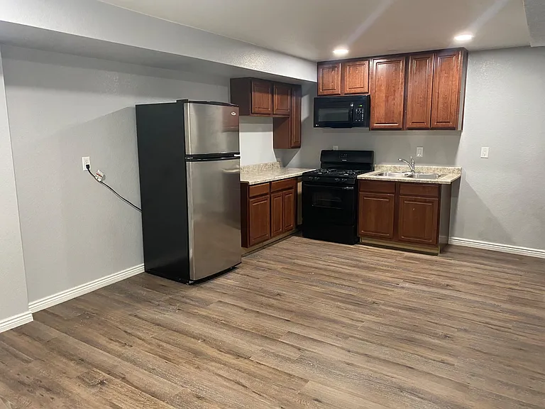 Compact kitchen with ample wood cabinetry, laminate counters, and a full appliance set including gas range and microwave.