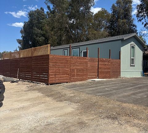 House is within larger lot with trucks and materials
