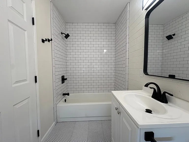 Bathroom with shower / tub combo, new penny tile and subway tile, toilet and vanity.