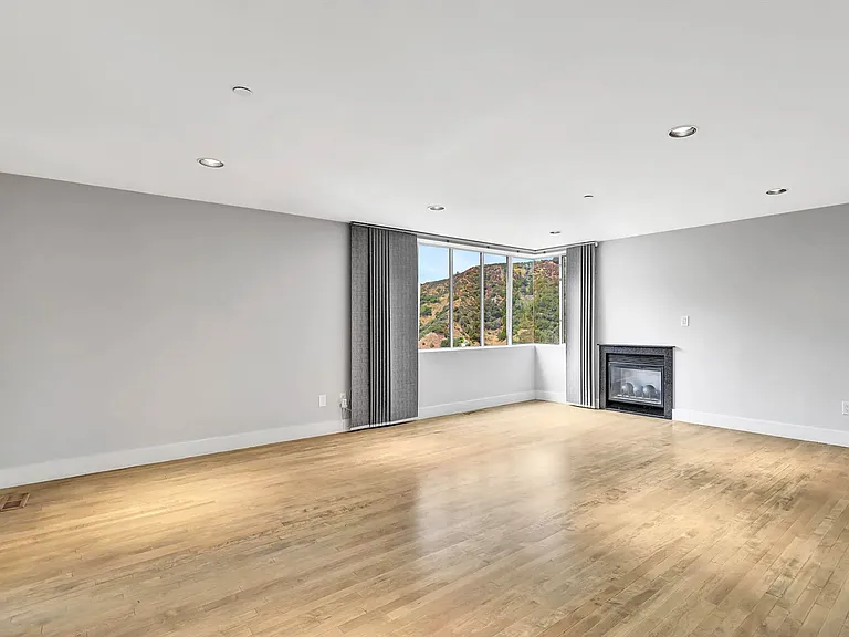 Spacious master bedroom with fireplace and view through remote blinds