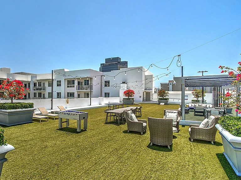 Luxury apartment rooftop lounge with outdoor seating, landscaped planters, and skyline views
