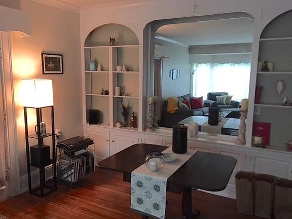 Open floor plan with large living and dining spaces featuring built-in cabinets and shelves, and a bay window for a reading nook/bench.