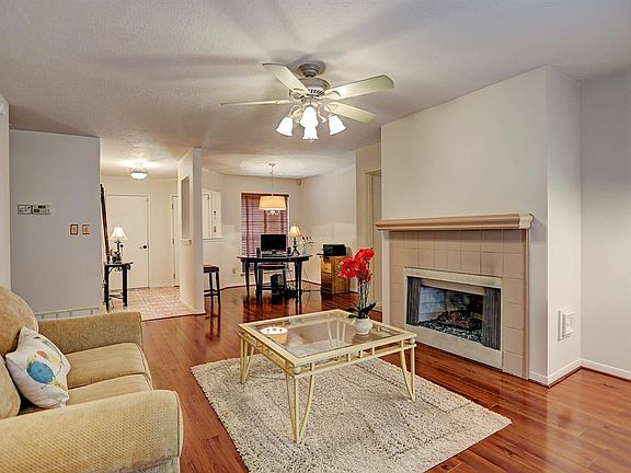 Relax after a long day in your large living room which features laminate wood floors, ceiling fan, and gaslog fireplace with tile surround and decorative mantle