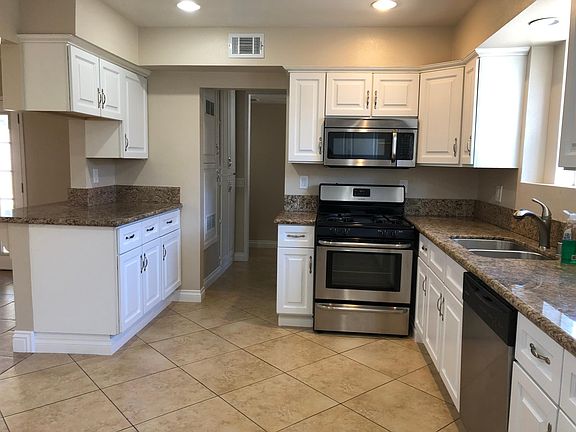 Stainless steel stove, over the range microwave, and dishwasher. Breakfast bar to left, sink to right