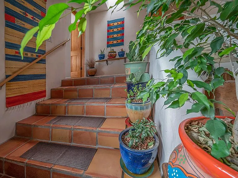 Saltillo tile and Mexican tapestries along staircase joining living room to second level bedroom (spit level).