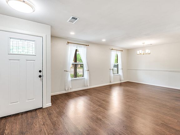Spacious interior with wood-finish flooring, white trim, and a white front entry door with leaded glass insert