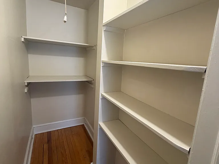 Hallway walk-in closet features plenty of built-in shelving for storage, as well as pull-down steps access to large attic space for additional storage.