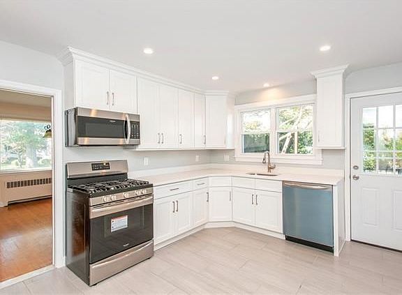 Newly renovated kitchen with stainless steel appliances, wood cabinets and quartz counters, showing the door to the patio