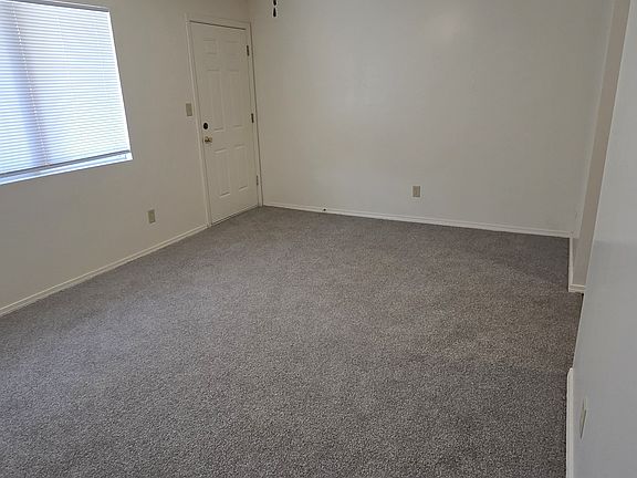Open living room with new carpet and ceiling fan, flowing right into the kitchen for an easy, connected layout.