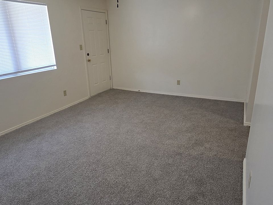 Open living room with new carpet and ceiling fan, flowing right into the kitchen for an easy, connected layout.
