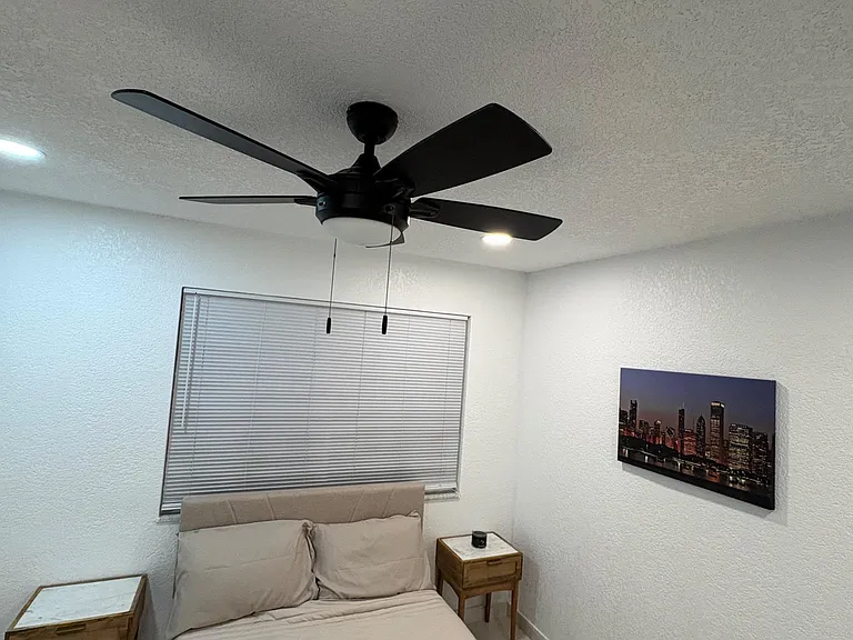 Neat bedroom with a ceiling fan, window with blinds, and space for a nightstand beside the bed.