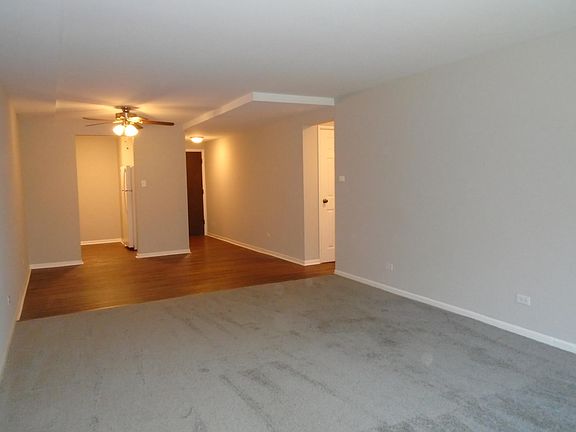 Living room looking towards dining room. Grey carpeting, walls painted light grey.