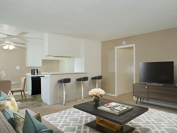 Kitchen with breakfast bar overlooking staged living area with carpet.