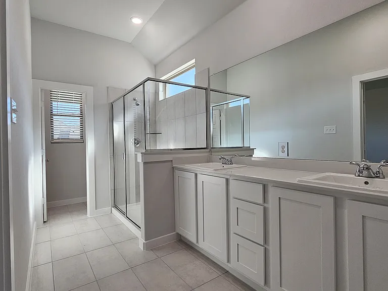 Spa-like primary bath with dual vanities, modern fixtures, and a large walk-in shower
