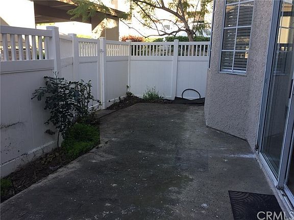 Fenced patio with gate leading to nearby carport