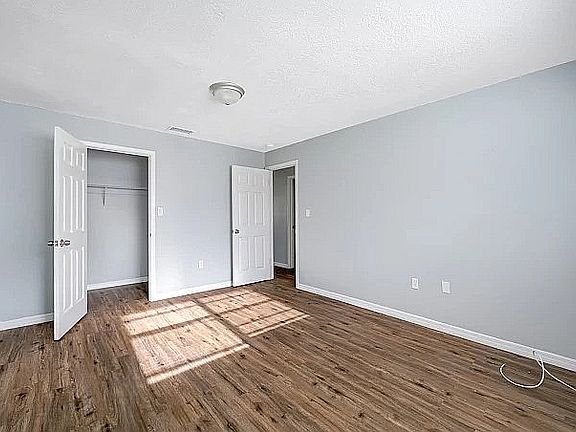 Bright and spacious bedroom featuring elegant wooden flooring and ample natural light, perfect for a cozy and modern retreat.