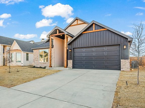 Modern single-story house with a dark gray garage, light brick and wood accents, large front window,
