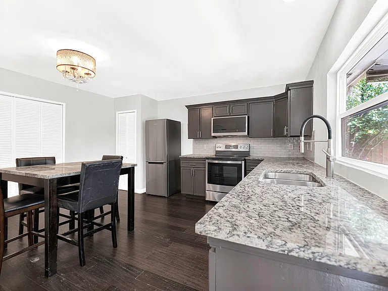 The kitchen's efficient layout provides abundant counter space and cabinetry, with a window above the sink and direct access to the backyard.