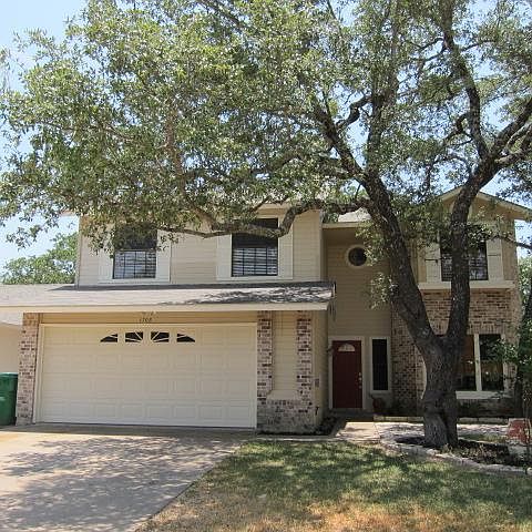 Front of house with shady oak trees and large 2 car garage.