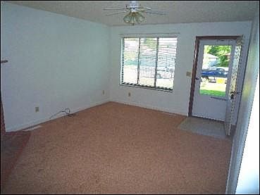 Living room has wood burning fireplace and ceiling fan