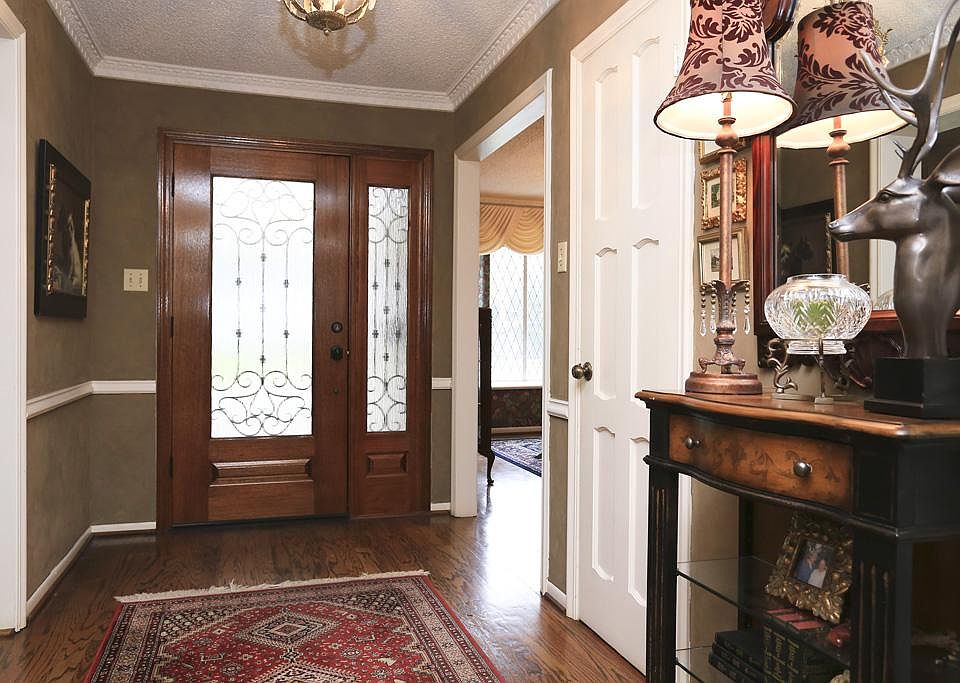 Beautiful glass and iron front door and side light welcomes you into the foyer accented with plank hardwood floors and lovely moldings.