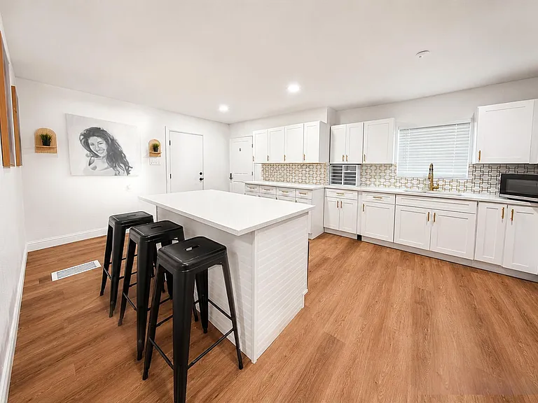 Spacious kitchen with a large eat-in island, ample white cabinetry, and stainless steel appliances for easy meal prep.