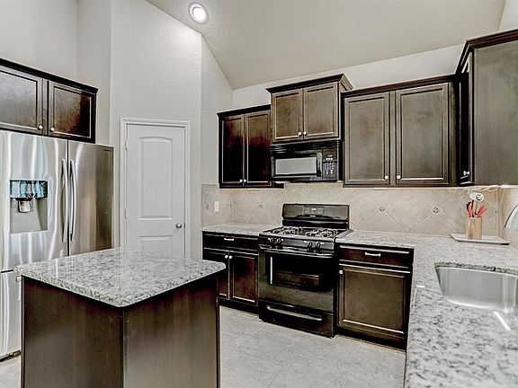 Island kitchen with gas range, under cabinet lighting and upgraded stainless steel sink.