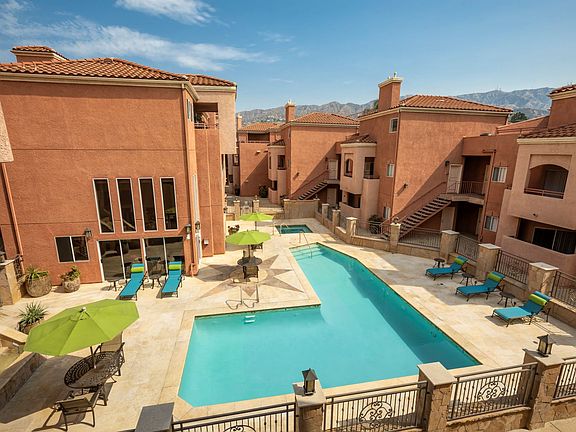 Aerial View of Pool, Jacuzzi and Patio with Lounge Chairs and Tables and Surrounding Buildings