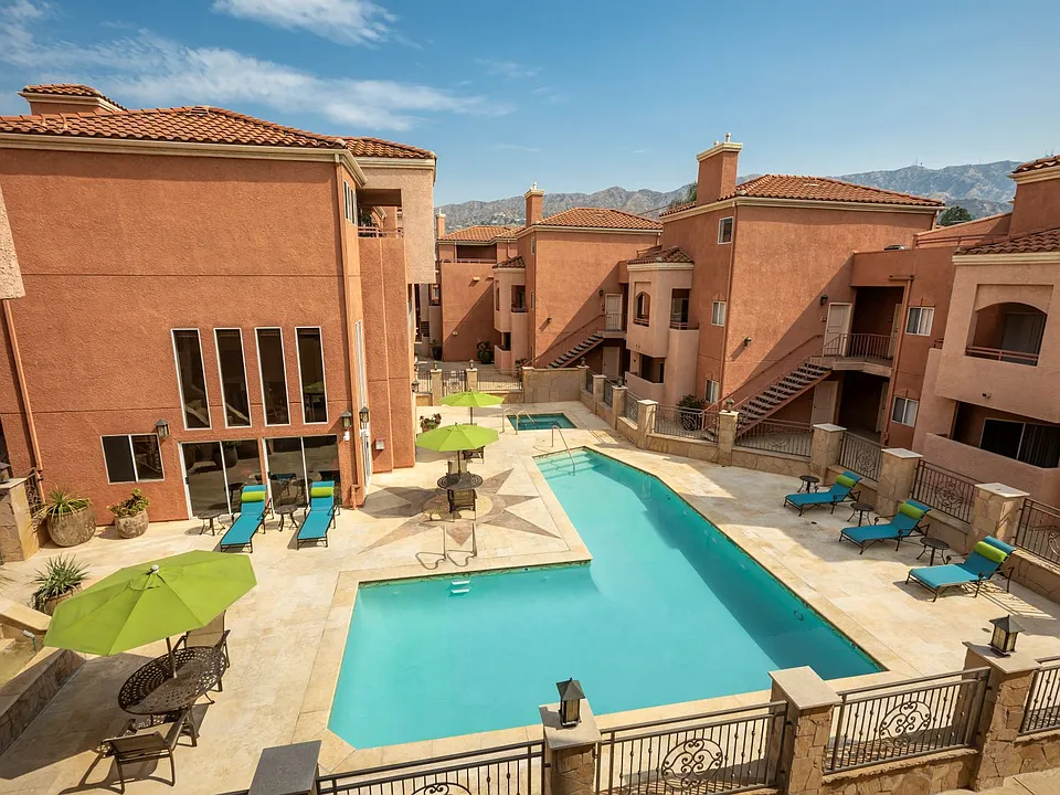 Aerial View of Pool, Jacuzzi and Patio with Lounge Chairs and Tables and Surrounding Buildings