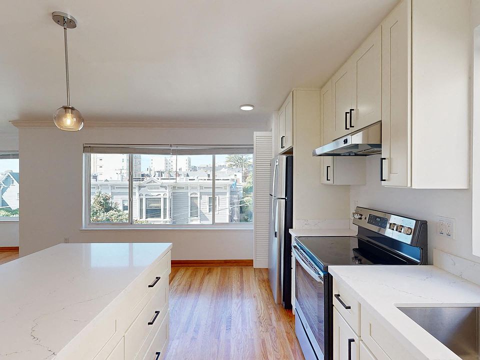 Kitchen with multiple cabinets, refrigerator, stove, range hood, and sink