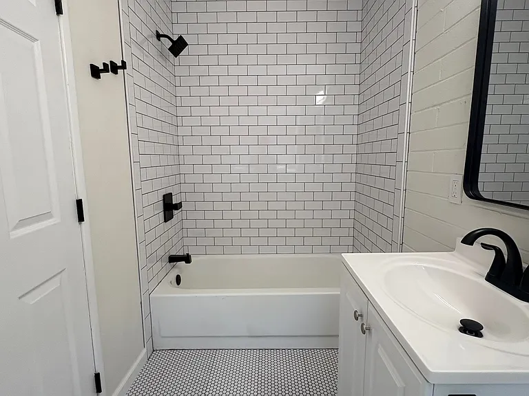 Bathroom with shower / tub combo, new penny tile and subway tile, toilet and vanity.