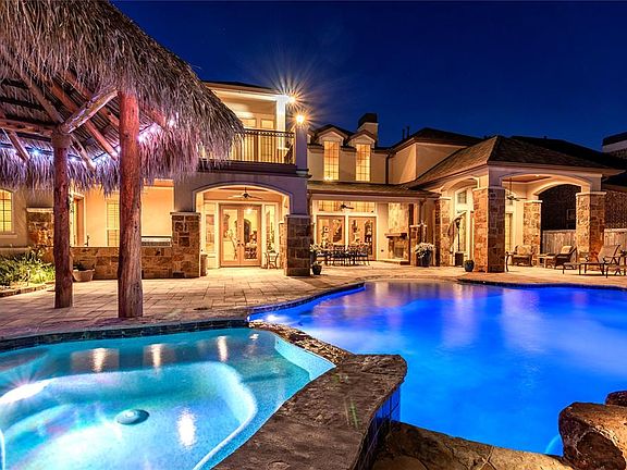 The back of the house has three gorgeous covered patios and a large balcony from the gameroom, perfect for outdoor entertaining. A fully fitted outdoor kitchen and bar on the left. Center is a larger patio with outdoor fireplace and French doors from