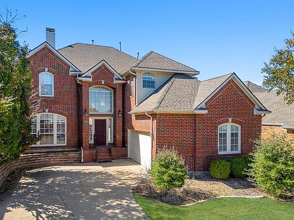 Traditional-style home with brick siding, concrete driveway, roof with shingles, a chimney, and an attached garage