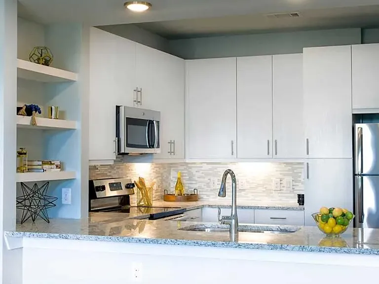 White finish package kitchen with tile backsplash, speckled granite countertop, and hard surface flooring